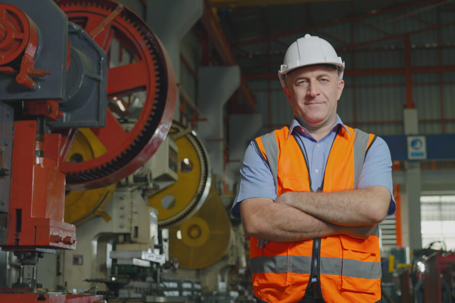 Engineer looking at the camera, Arms crossed and smiling in a factory