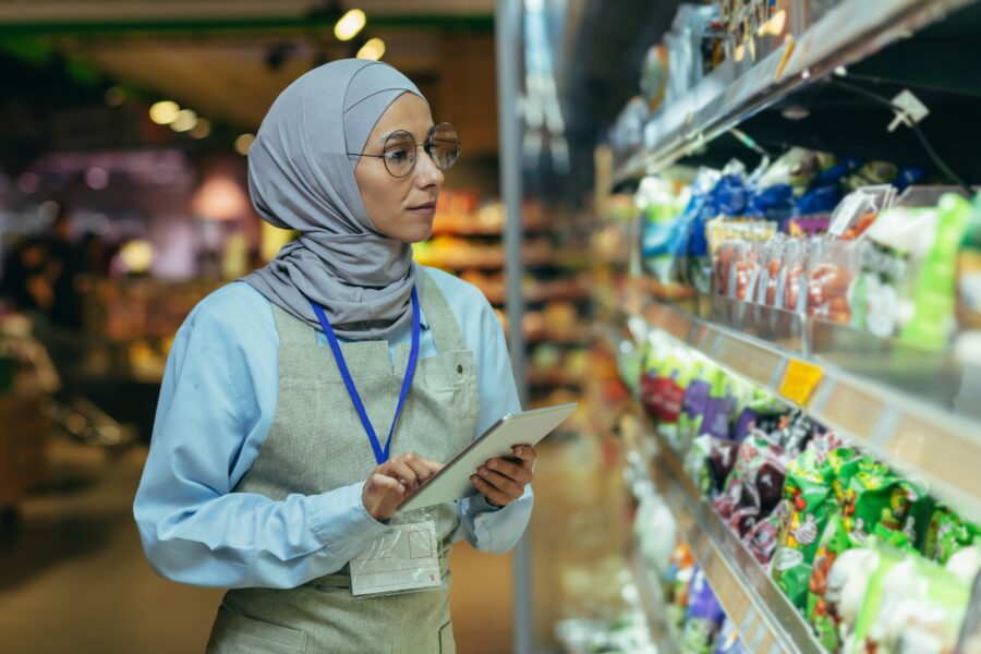 woman Seller in super market in hijab with tablet checking products using pocket computer