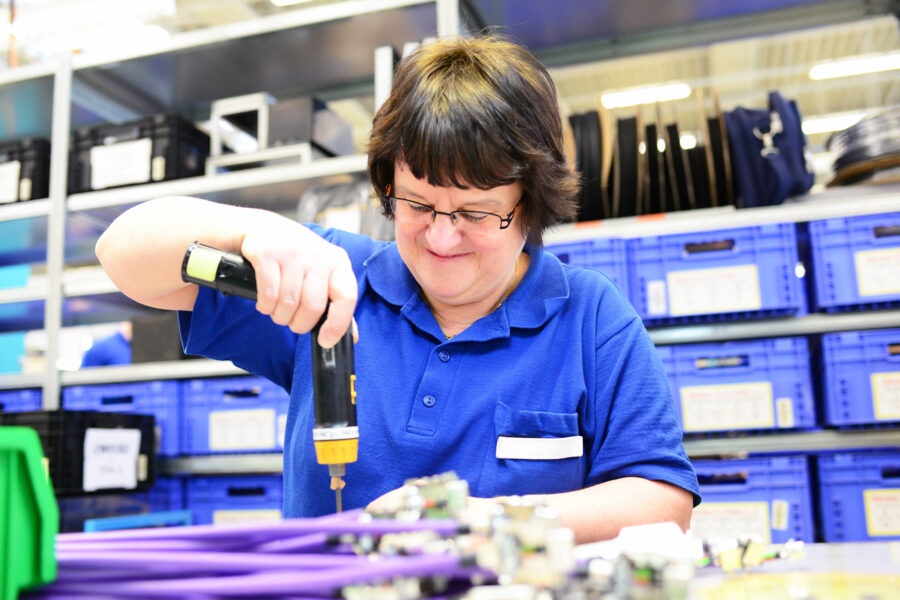 older woman assembles electronic components in a hi-tech factory