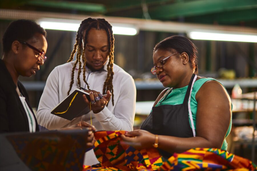 Textile industry employer and employees looking at laptop having a production meeting