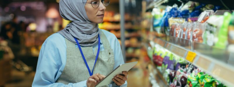 woman Seller in super market in hijab with tablet checking products using pocket computer