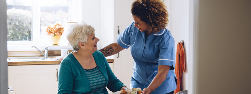 Care worker giving an old lady her dinner in her home.